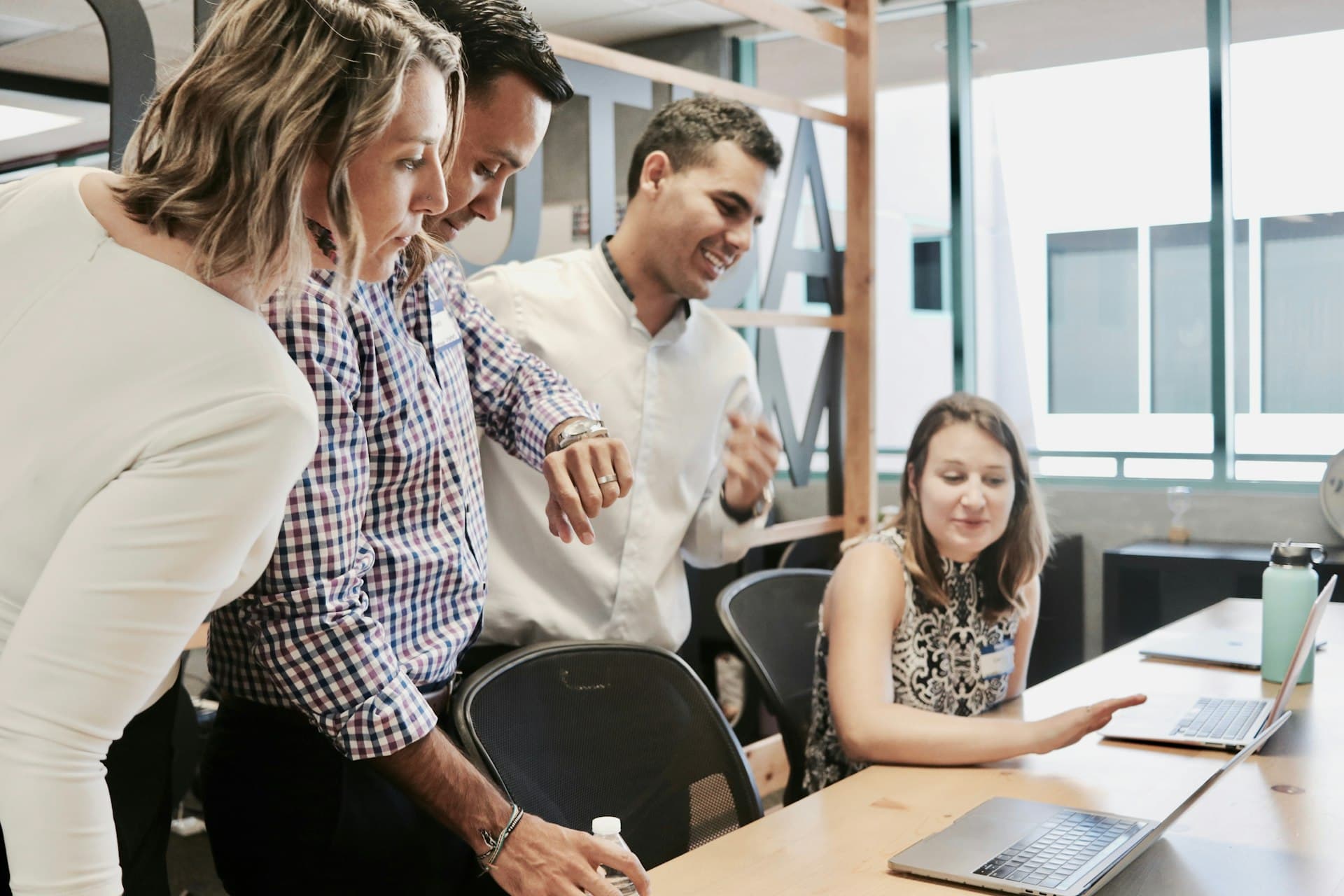 A team gathered around a laptop setting up their workspace together